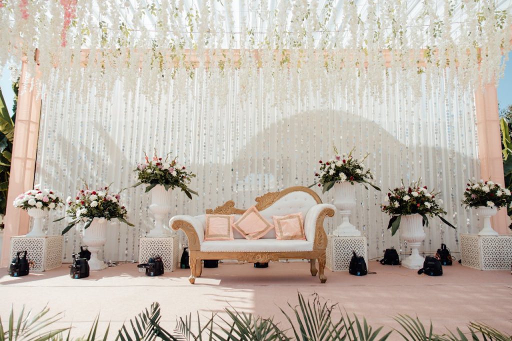 Luxurious outdoor wedding stage adorned with floral arrangements and elegant seating.